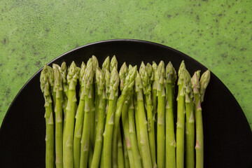 Fresh asparagus on a black dish and green background, close-up
