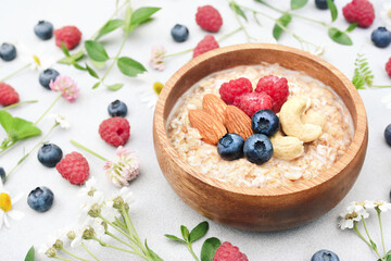 Morning oat with raspberry, blueberry and nuts, summer vegan oatmeal for healthy diet, selective focus