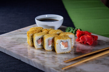 Sushi. A serving of fresh Japanese rolls on a marble board with soy sauce, wasabi and pickled...