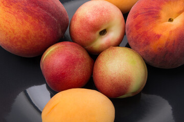 Apricots, peaches and nectarines on a black plate close-up