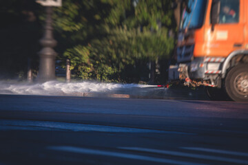 Cleaning flusher sweeper machines washes the city streets road with water spray, group of municipal...