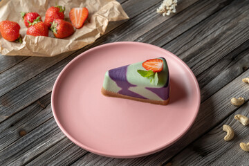 Blueberry cake, lemon, mint. Vegan, lactose free and sugar free. Laid on a pink plate, decorated with strawberries.