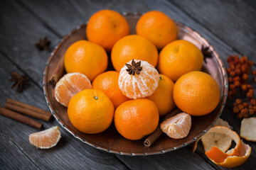 Tangerines in a copper dish on the old wooden background, table. Retro vintage style, selective focus.