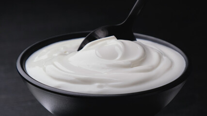 Bowl of sour cream on black background, greek yogurt