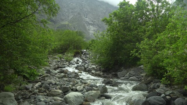 Wild mountain river close up with clear stream. Detail static b-roll footage of creek with stone boulders flowing.
