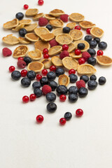 Mini pancakes and berries on white background.