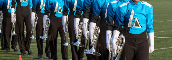 Marching band on a field. Marching in a line with trumpets and other instruments playing music.