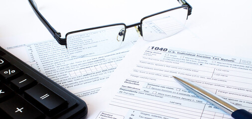 US tax form 1040 with a silver pen, glasses and calculator