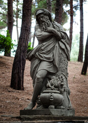 Statue of the ancient Greek God in the forest among the trees. Zeus.