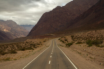 Adventure. Desert road. View of the asphalt highway across the arid desert and mountains. 