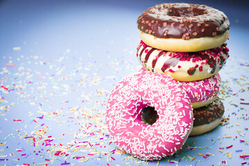 Fototapeta na wymiar Multicolored sweet donuts with colourful decorations on violet background.