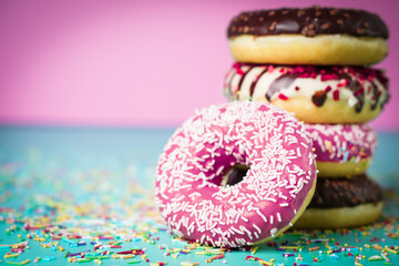 Multicolored sweet donuts with decoration on colourful background.