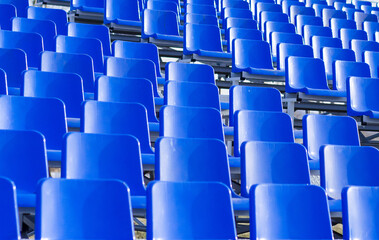 Background of blue plastic seats in the stands.  Empty seats in the stadium. Places for fans and spectators.