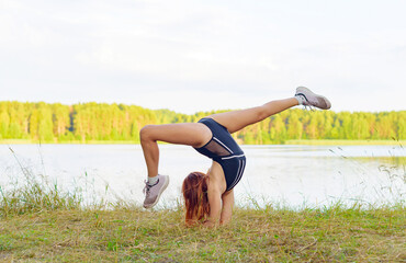 a girl in a swimsuit and sneakers does exercises from rhythmic gymnastics in nature on the river...