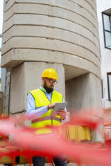 Architect in protective helmet using digital tablet