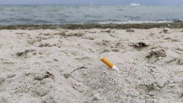 Cigarette butt in the sand at the sea shore. In Copenhagen, Denmark, Europe