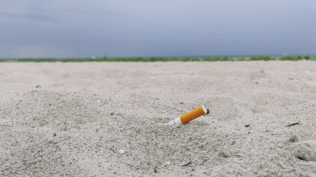 Cigarette butt in the sand at the sea shore. In Copenhagen, Denmark, Europe
