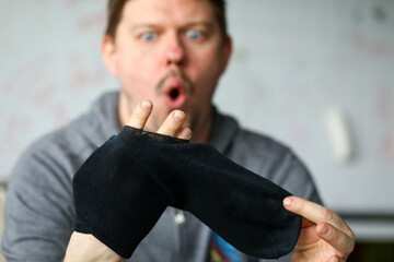 Man sitting at home surprised by big hole socks
