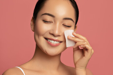 Beauty treatment and skin care. Beautiful Asian model using absorbing sheet.
