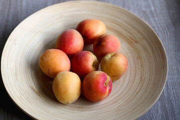 Wooden bowl with fresh organic apricots on the table. Selective focus.