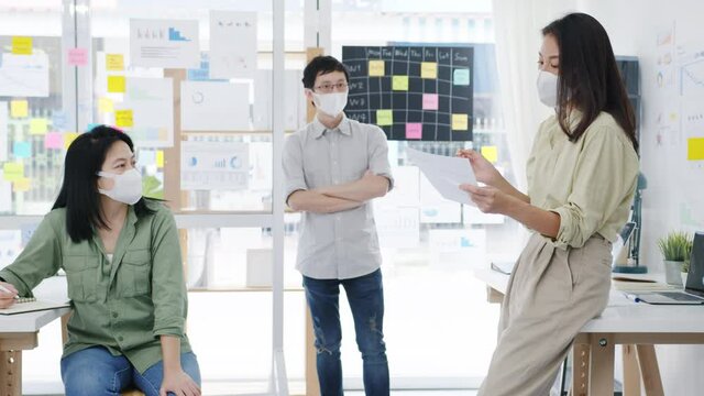 Asia businesspeople meeting brainstorming ideas conducting business presentation ideas project colleagues and wear protective face mask back in new normal office. Lifestyle and work after corona virus