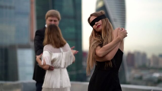 handsome man is dancing with beautiful woman, blindfold lady dancing alone, adultery and passion