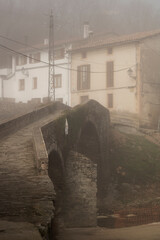 Fototapeta na wymiar Foggy town and medieval bridge