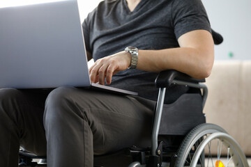 Man sitting in wheelchair working with laptop computer