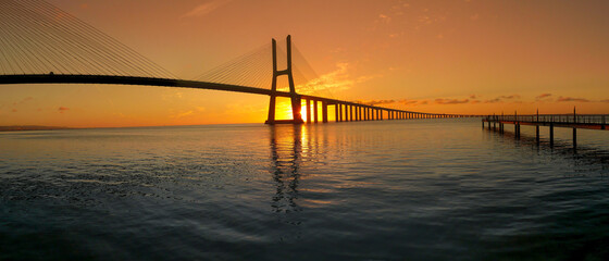 Fototapeta na wymiar Beautiful sunrise at Vasco da Gama Bridge, the longest bridge in Europe, who spans the Tagus River in Lisbon, Portugal.