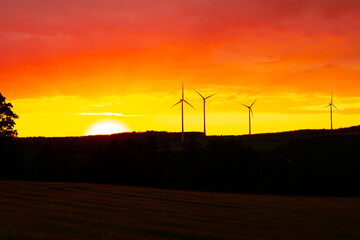 Fototapeta na wymiar Orangener Sonnenuntergang mit Windturbinen im Hintergrund