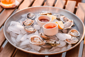 Oyster platter with minced shallot in red vinegar and horseradish tomato sauce. Seafood plate. Ocean meal. Raw seafood. Lemon slices. Fresh and nutritional dinner. Luxury meal. Fancy dinner.