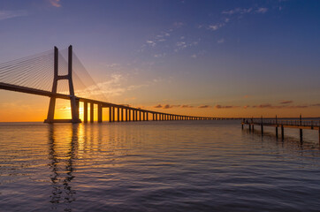 Naklejka na ściany i meble Sunrise at Vasco da Gama Bridge, the longest bridge in Europe, who spans the Tagus River, in Lisbon, Portugal.