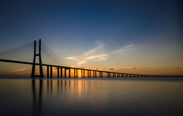 Obraz na płótnie Canvas Sunrise at Vasco da Gama Bridge, the longest bridge in Europe, who spans the Tagus River, in Lisbon, Portugal.