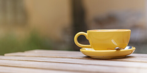 lonely yellow cup of coffee on wooden table at empty street cafe crisis in food industry concept