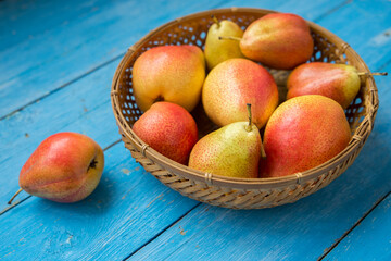 Ripe pears in a wooden bowl on an old blue table made of boards