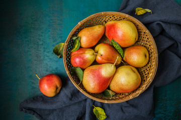 Ripe pears on a plate on a blue-green background close-up.