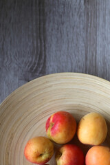 Wooden bowl with fresh organic apricots on the table. Top view.