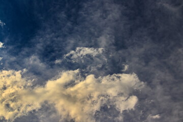 white clouds lit by the afternoon sun dissolving under a misty blue sky.