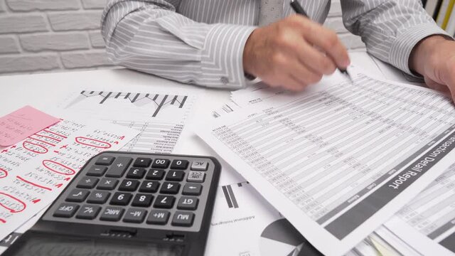 Business analysis and accounting concept - businessman working with document, spreadsheet, using calculator, tablet pc. Office desk closeup. 