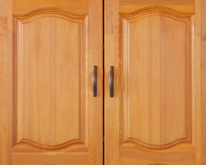 Yellow wooden cabinet door with brown handles. Front close up view.