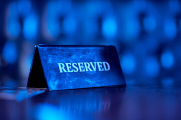 Reserved plate on night club, reserved sign. Blue light.