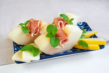  Grube plastry soczystego, słodkiego melona z szynką prosciutto ozdobione listkami mięty © Monika
