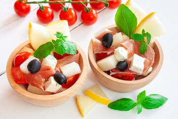 Sałatka z szynką parmeńską, melonem, pomidorami koktajlowymi serem feta i oliwkami ozdobiona listkami mięty i bazylii © Monika