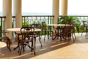 outdoor summer terrace, with cast iron.stylish furniture, in a cafe at sunset