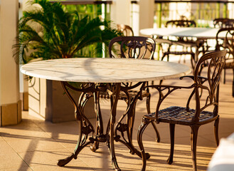 outdoor summer terrace, with cast iron.stylish furniture, in a cafe at sunset