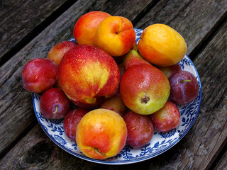 summer basket of fruits - pear, nectarine, plum and apricots on a wooden background