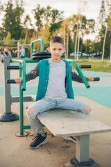 Fototapeta na wymiar A boy of 11 years old is engaged in a simulator on the sports ground. Posing and looking at the camera. Healthy lifestyle concept of a teenager. Vertical photo