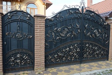 black iron gate and door with wrought iron pattern and brown bricks in the wall on the sidewalk in the street