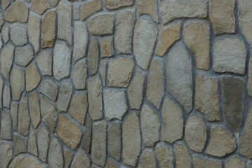 gray brown texture of stones in the wall of the fence on the street