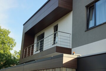 one metal open gray balcony on the facade of a  brown private house